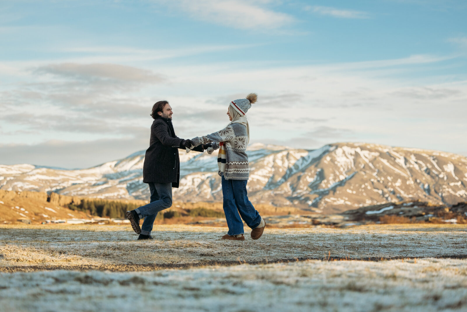 Jess and Aaron spinning together during their Iceland couples session with mountains in the background