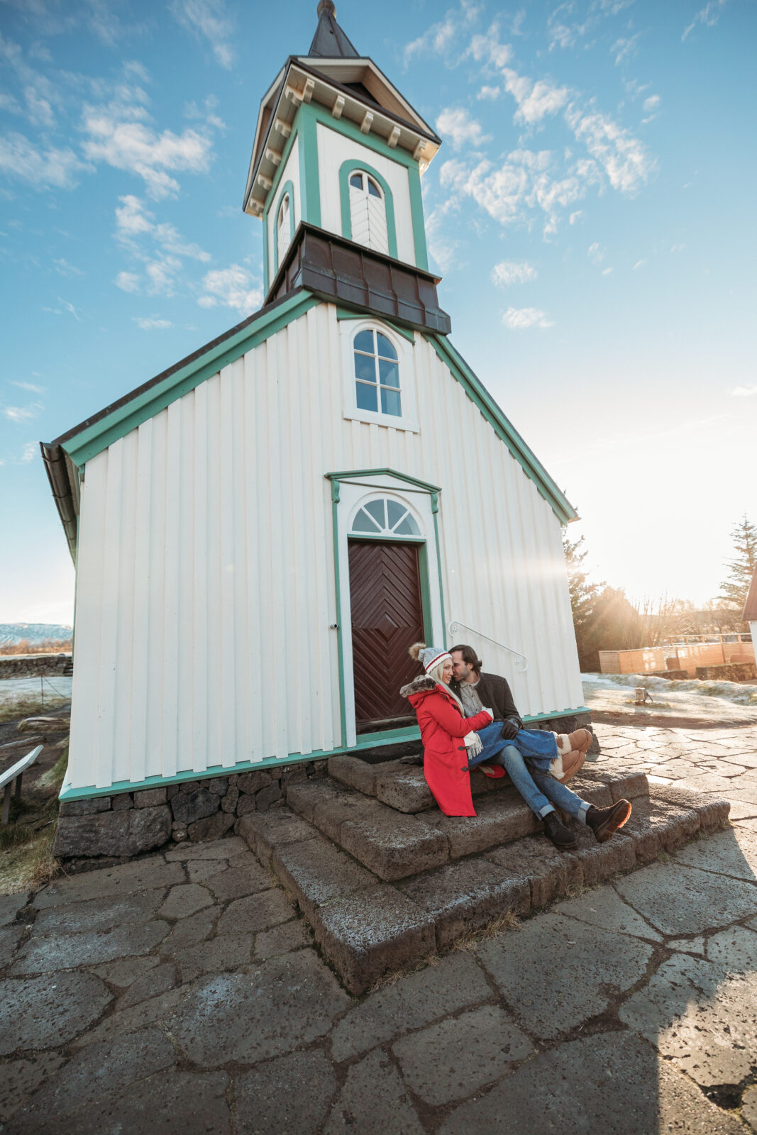 Jess and Aaron sitting on church steps during an Iceland couples session before their elopement