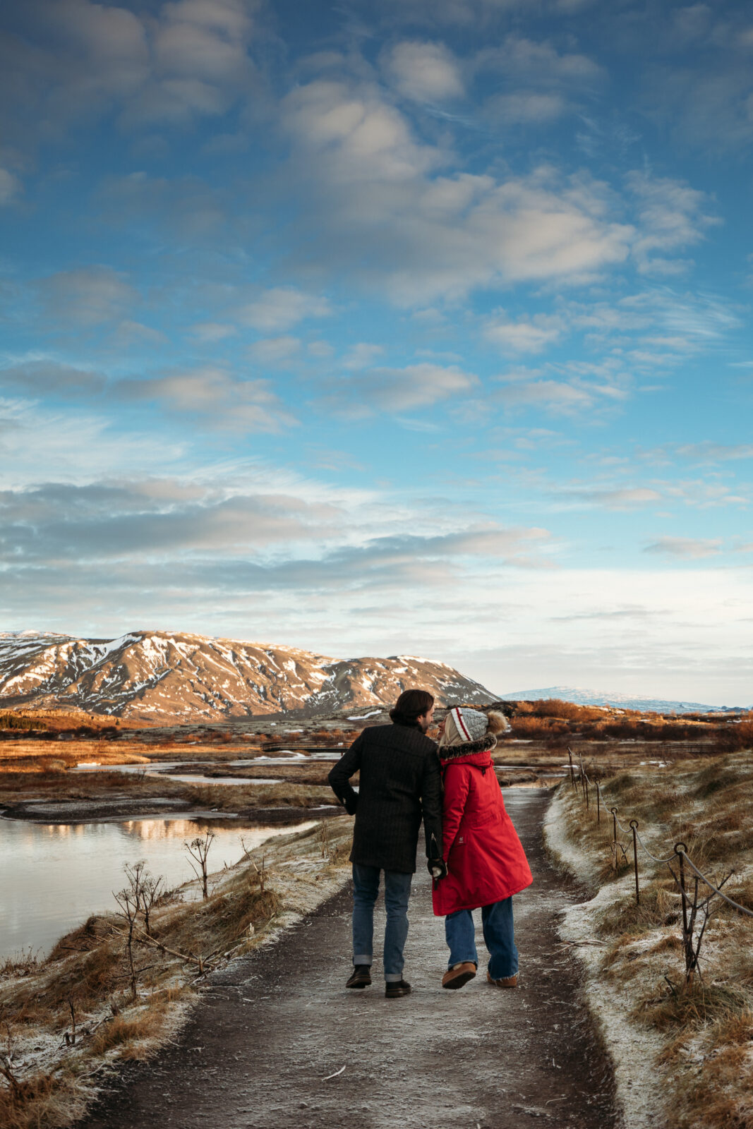 Couple walking away together on an Iceland road with mountains in the distance