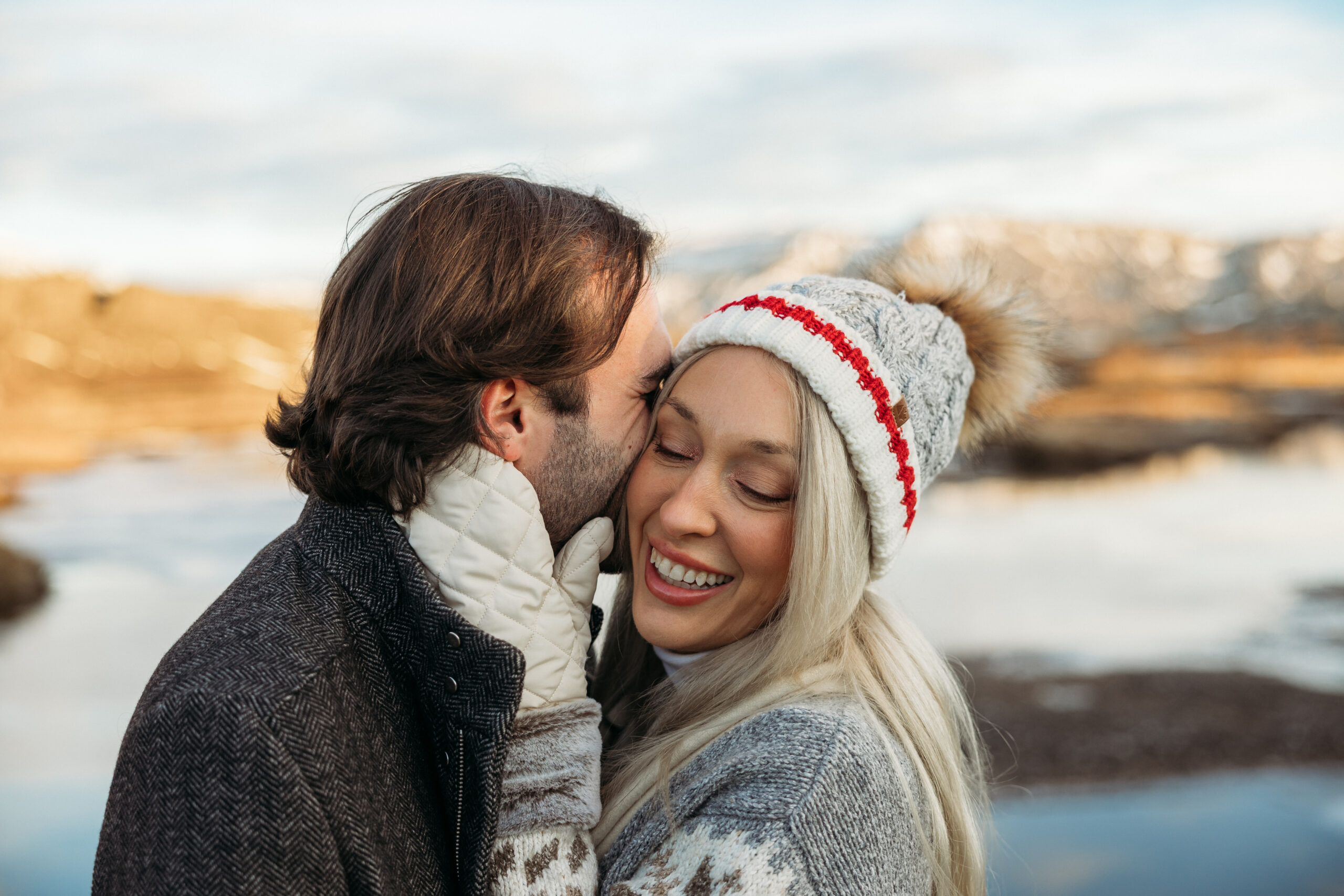 Jess and Aaron embracing in front of Icelandic mountains during a winter couples session.